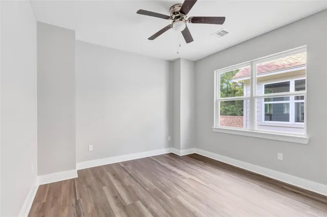 a view of empty room with wooden floor and fan