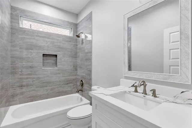 a bathroom with a granite countertop bathtub shower sink vanity mirror and toilet