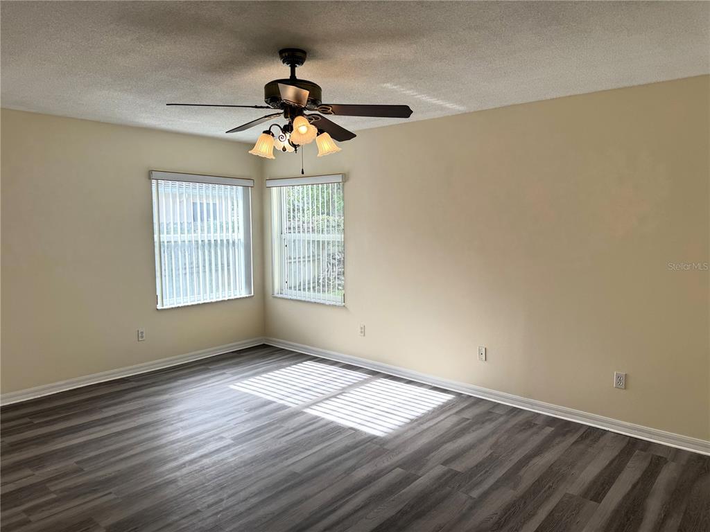 54 Westmount Lane Palm Coast, FL 32164 - Photo 22 of 32 an empty room with wooden floor chandelier fan and windows