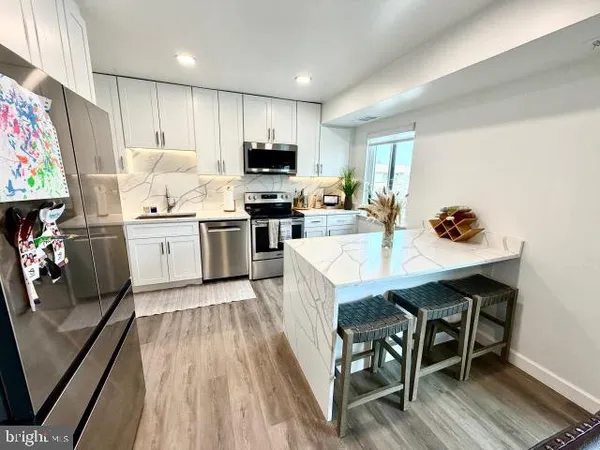 a kitchen with a sink a stove a refrigerator cabinets and wooden floor