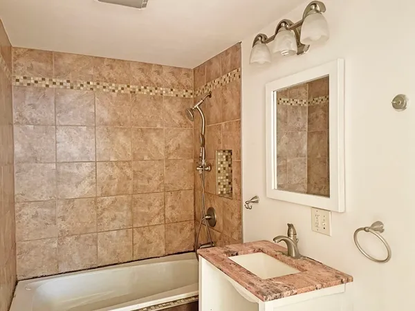 a bathroom with a granite countertop sink a mirror and shower