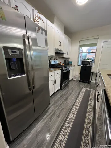 a kitchen with granite countertop stainless steel appliances a counter top space and cabinets