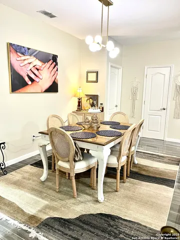 a dining room with wooden floor a chandelier a wooden table and chairs