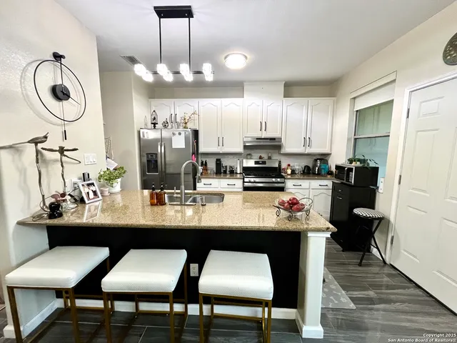 a kitchen with kitchen island granite countertop a sink cabinets and wooden floor