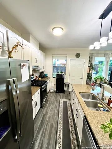 a kitchen with granite countertop a sink a counter space appliances and cabinets