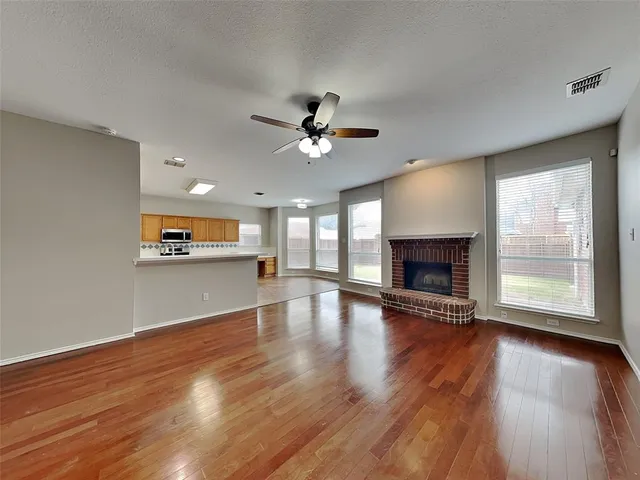an empty room with wooden floor fireplace and windows