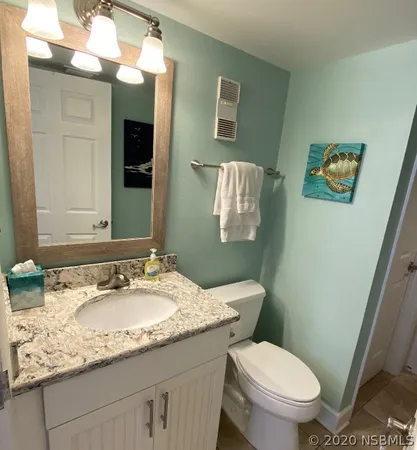 a bathroom with a granite countertop toilet sink and mirror