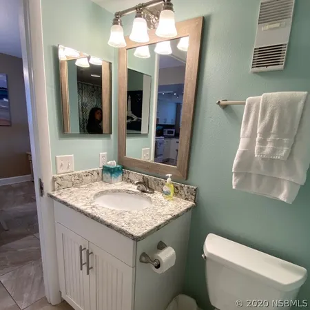 a bathroom with a granite countertop sink toilet and mirror