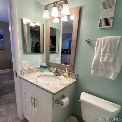 a bathroom with a granite countertop sink toilet and mirror