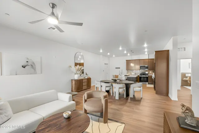 a living room with furniture kitchen view and a wooden floor
