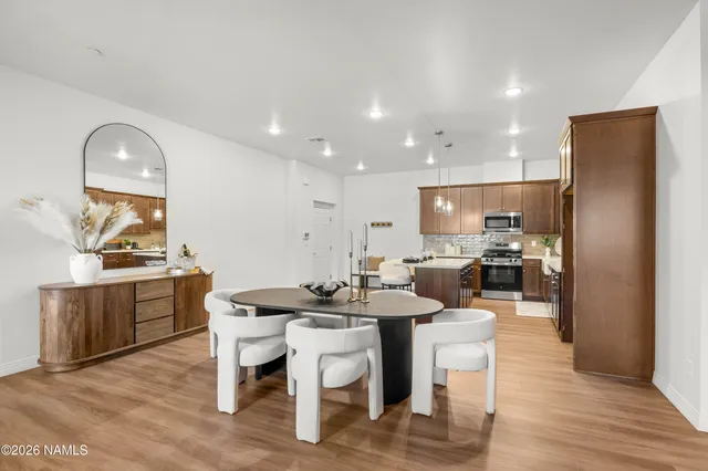 a kitchen with a dining table chairs and wooden floor