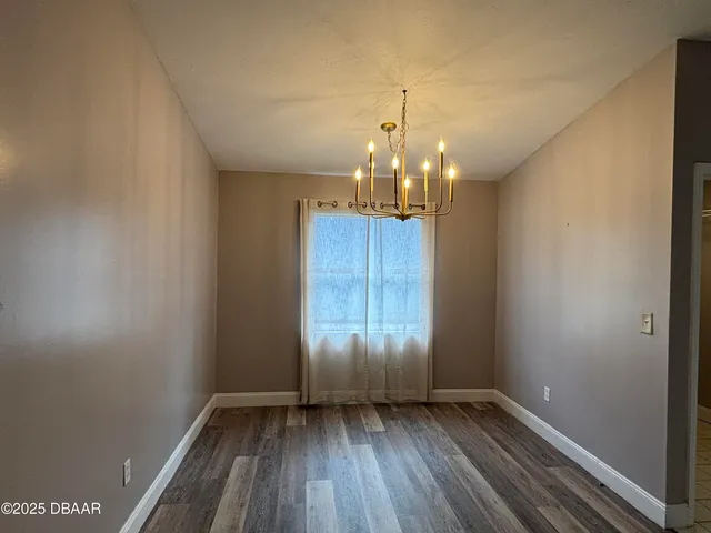 a view of an empty room with wooden floor and window