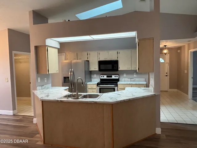 a kitchen with kitchen island granite countertop stainless steel appliances a stove refrigerator sink and microwave