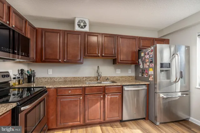 a kitchen with stainless steel appliances granite countertop a sink a stove a microwave and cabinets