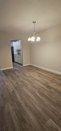an empty room with wooden floor and chandelier