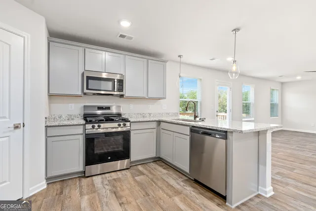 a kitchen with stainless steel appliances granite countertop a stove top oven a sink dishwasher and a refrigerator