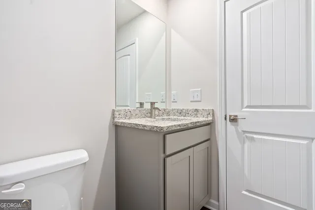a bathroom with a granite countertop sink and a toilet