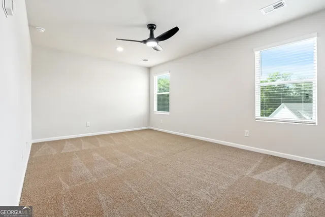 an empty room with ceiling fan and windows