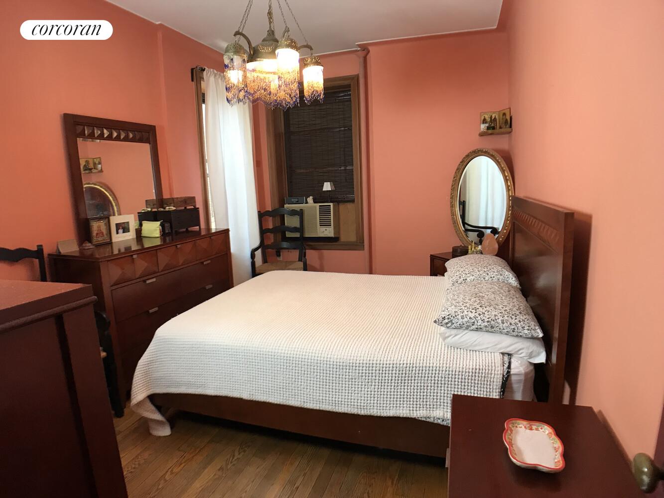790 Riverside Drive, Unit 7C Manhattan, NY 10032 - Photo 7 of 12 a bedroom with a bed mirror and a chandelier
