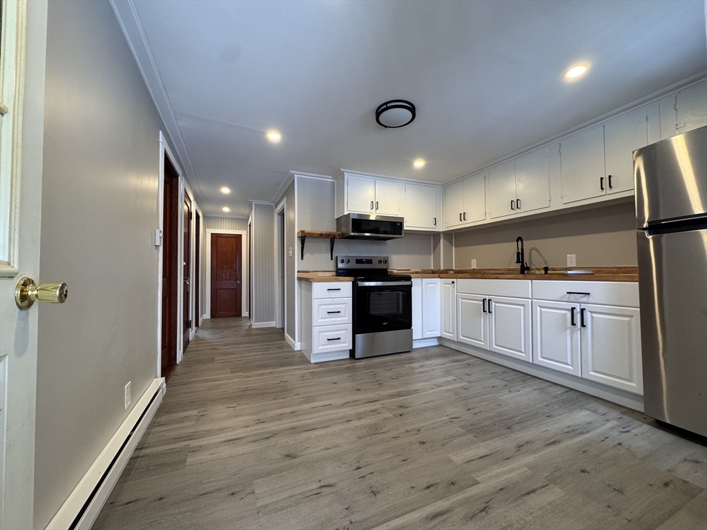 4 James Street, Unit 2 Dudley, MA 01571 - Photo 2 of 15 a large kitchen with stainless steel appliances kitchen island a large counter top and a stove top oven