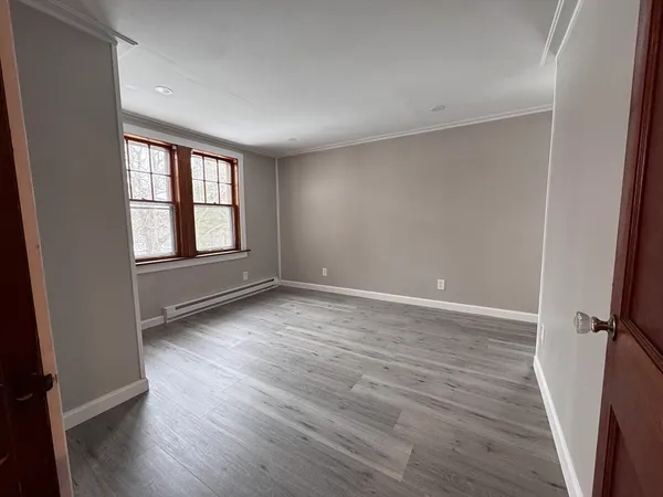 an empty room with wooden floor and windows