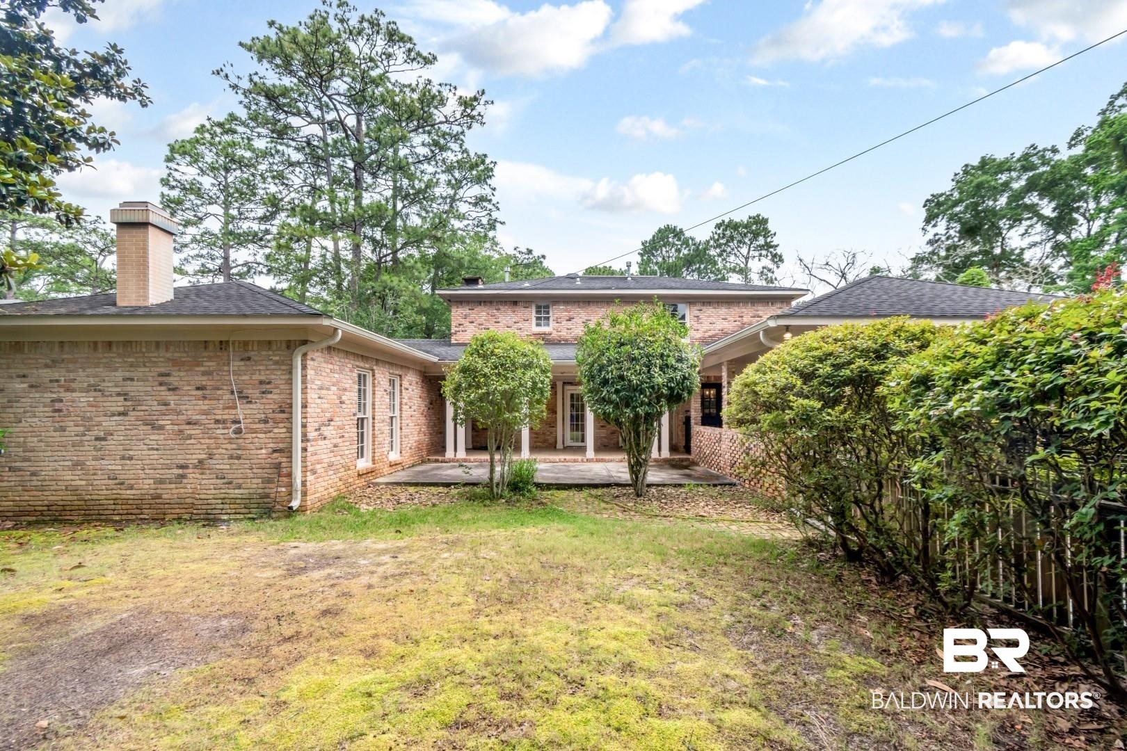 4776 Falls Church Road Mobile, AL 36608 - Photo 38 of 45 Brick exterior residence featuring multiple windows, a prominent chimney, and a covered patio area