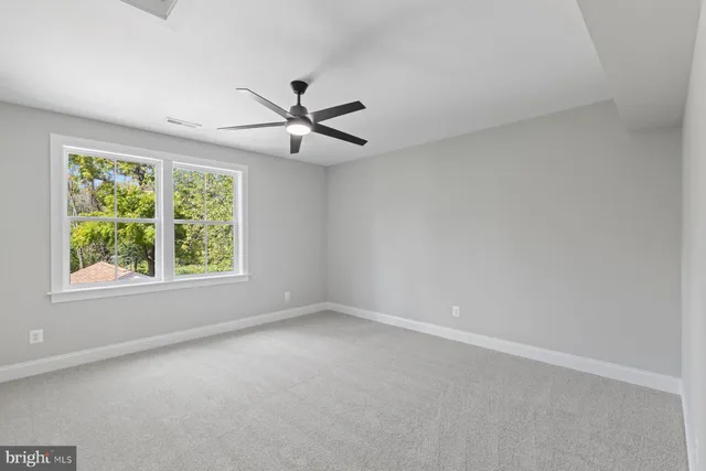 an empty room with a window and a fan