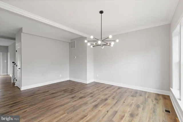 a view of an empty room with wooden floor closet and a living room