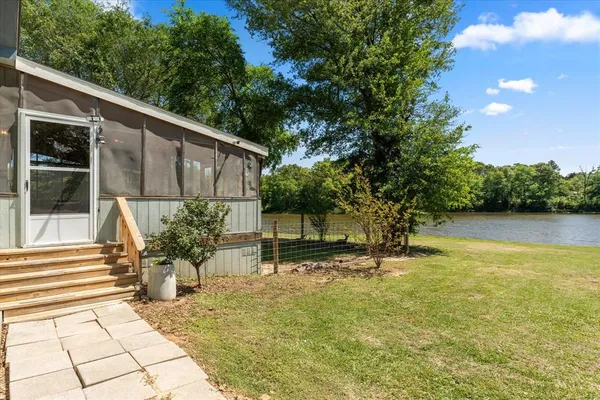 a backyard of a house with plants and large tree