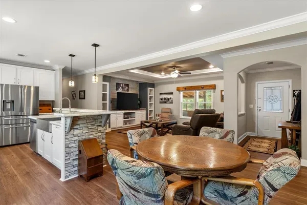 a living room with stainless steel appliances granite countertop furniture a fireplace a flat screen tv and a large window