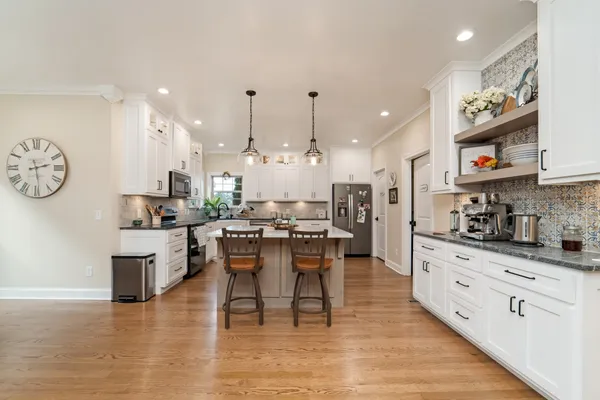 a large white kitchen with lots of counter space and stainless steel appliances