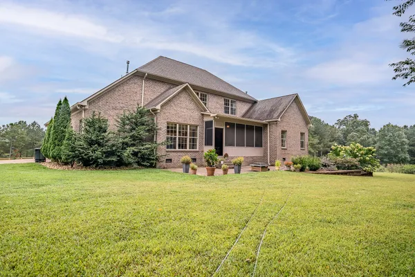 a front view of house with yard and trees in the background