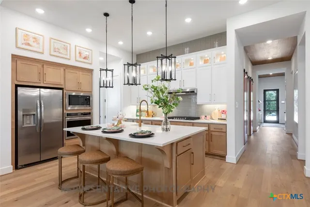 a kitchen with kitchen island a large island in the center windows a sink and a counter top space