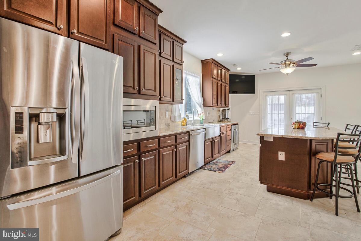 201 Charles Road Linthicum Heights, MD 21090 - Photo 13 of 50 a large kitchen with stainless steel appliances granite countertop a refrigerator a sink dishwasher a dining table and chairs with wooden floor