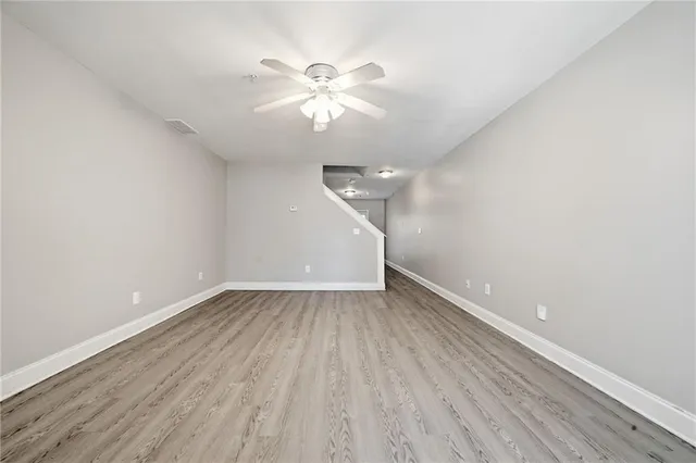 an empty room with wooden floor and fan