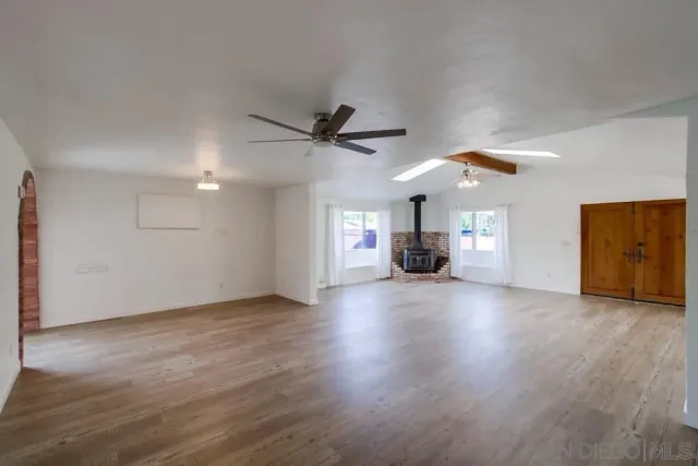 a view of a livingroom with a fireplace a ceiling fan and wooden floor