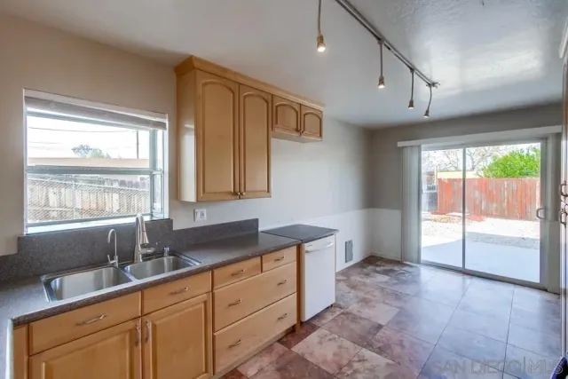 a kitchen with granite countertop a sink and white cabinets next to a window