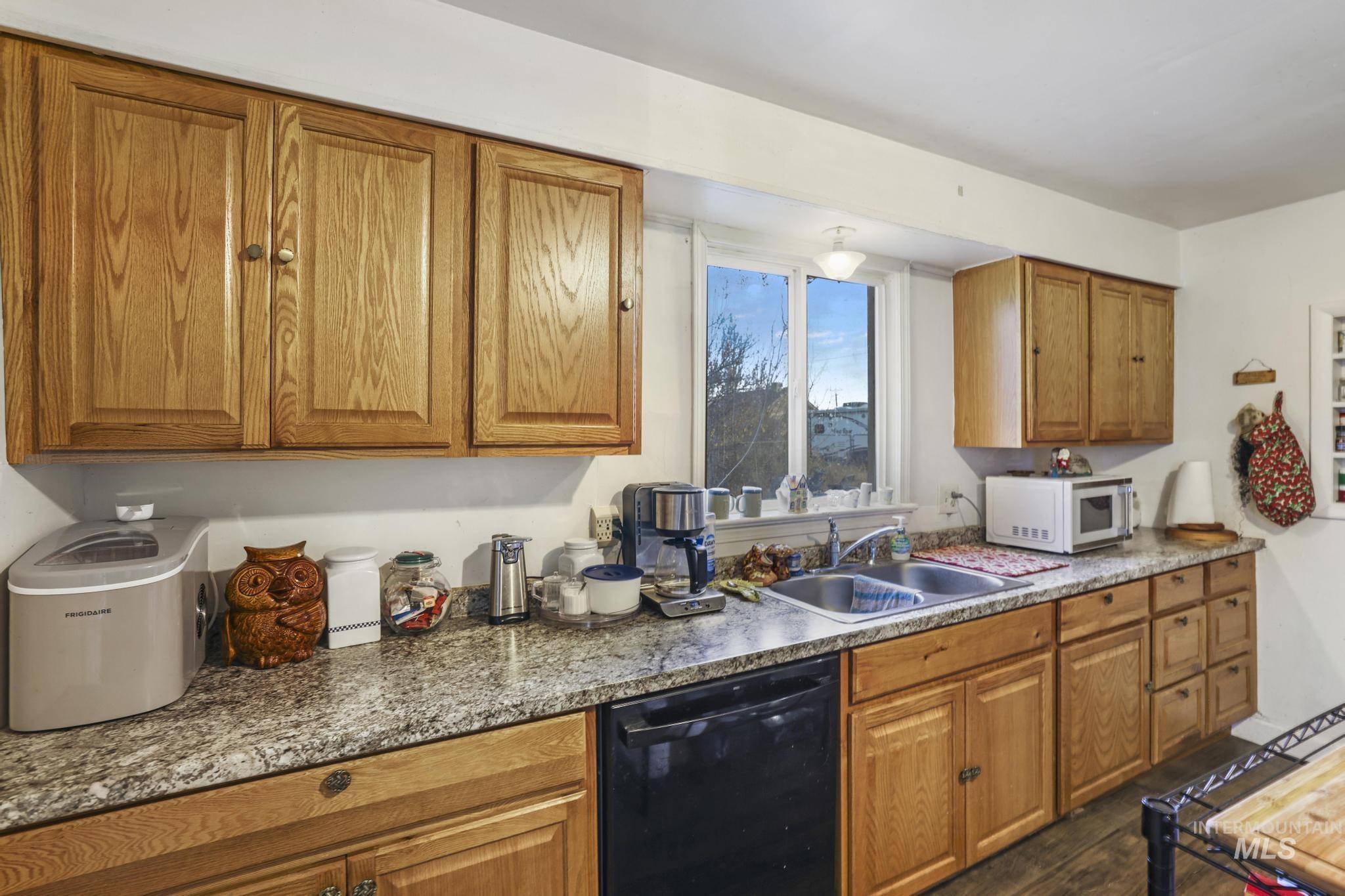 669 Locust Street South Twin Falls, ID 83301 - Photo 7 of 37 Kitchen with brown cabinets, dishwasher, white microwave, and dark wood-style flooring