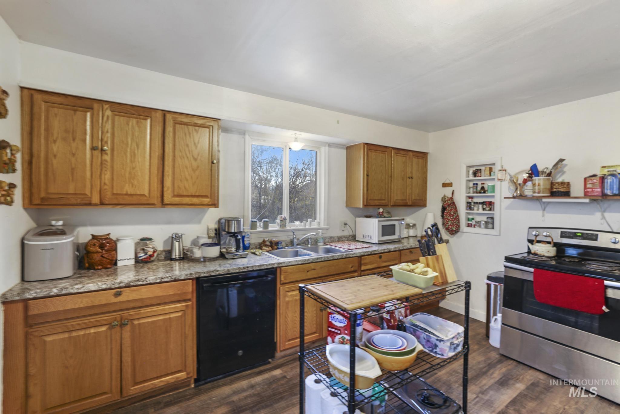 669 Locust Street South Twin Falls, ID 83301 - Photo 9 of 37 Kitchen with brown cabinets, stainless steel range with electric cooktop, black dishwasher, white microwave, and dark wood finished floors