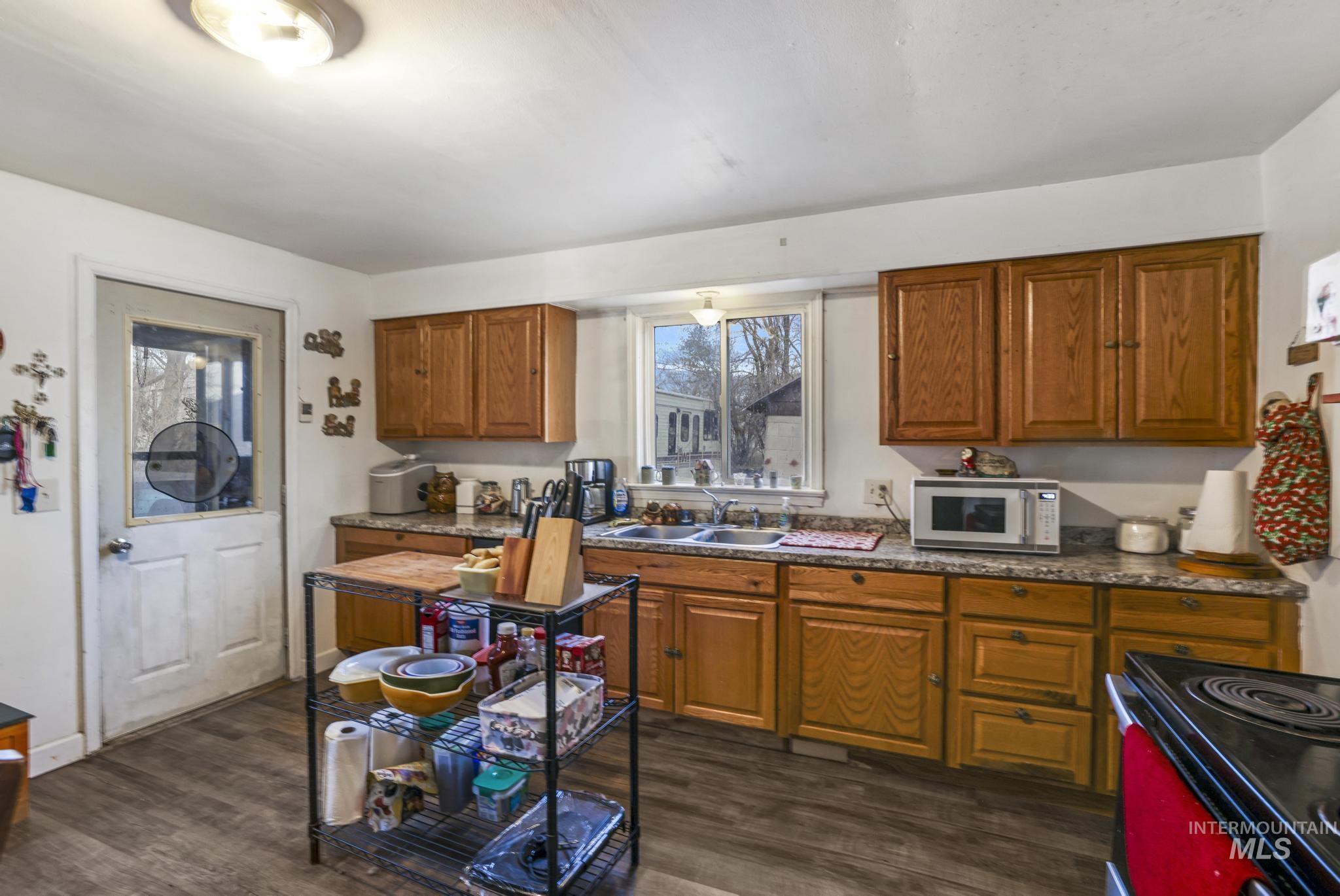 669 Locust Street South Twin Falls, ID 83301 - Photo 10 of 37 Kitchen featuring black range with electric stovetop, brown cabinets, white microwave, and dark wood-type flooring