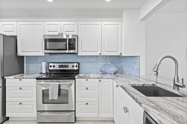 a kitchen with white cabinets stainless steel appliances and sink