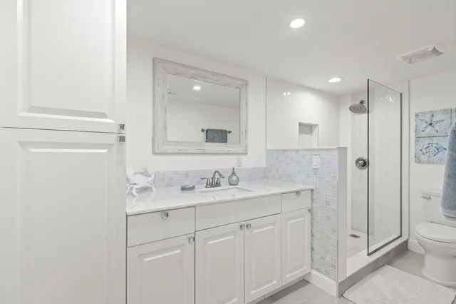 a bathroom with a toilet a sink a mirror and a shower