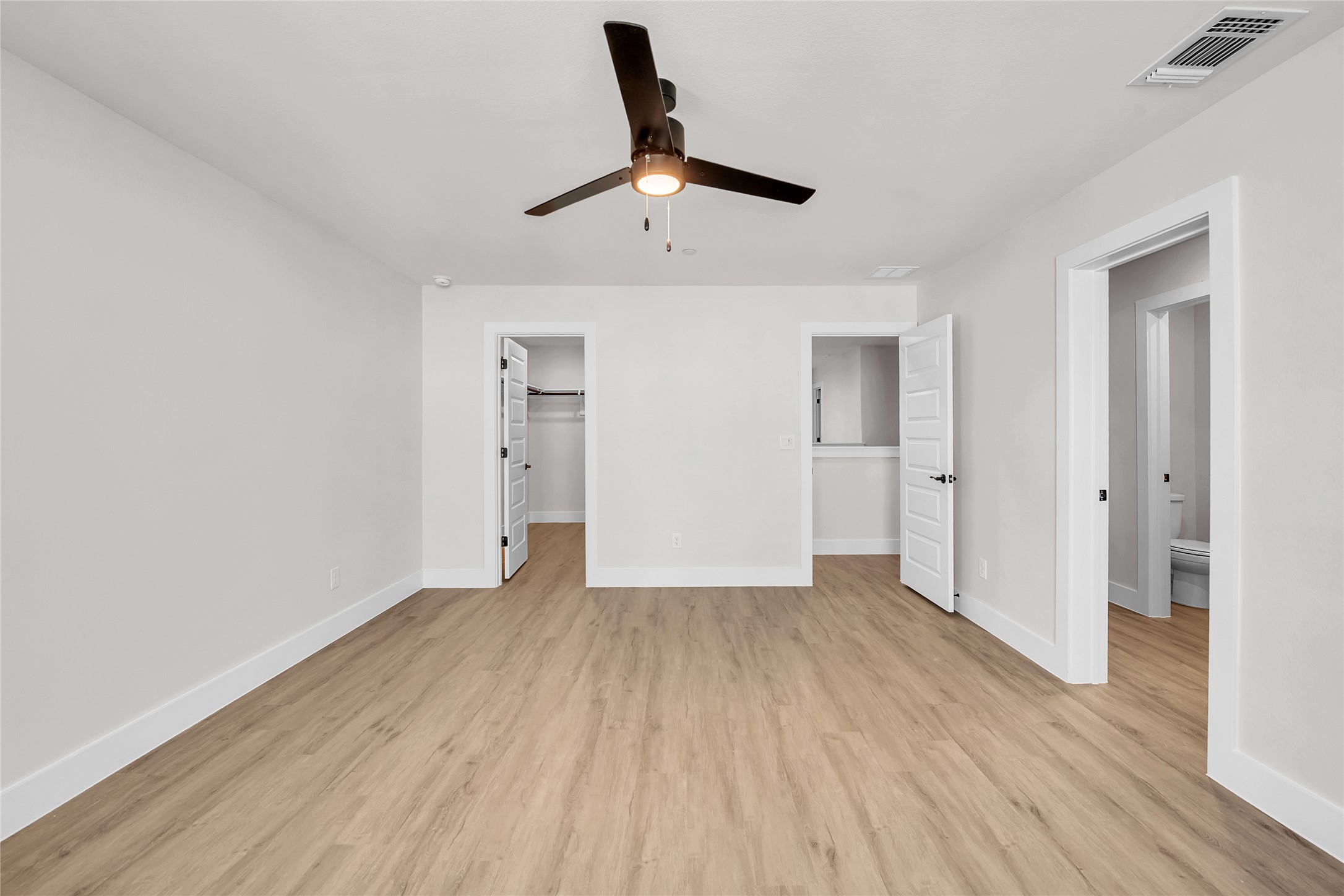 9312 Curious Squirrel Street Austin, TX 78744 - Photo 11 of 22 an empty room with wooden floor a ceiling fan and kitchen view