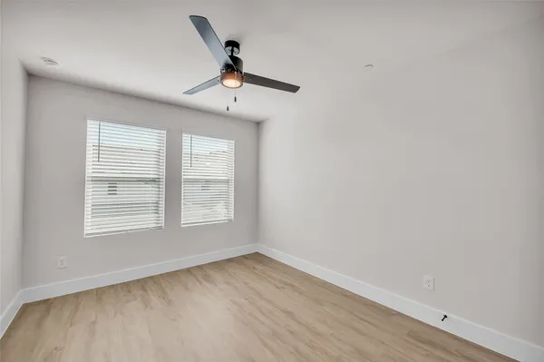 a view of an empty room with a window and wooden floor