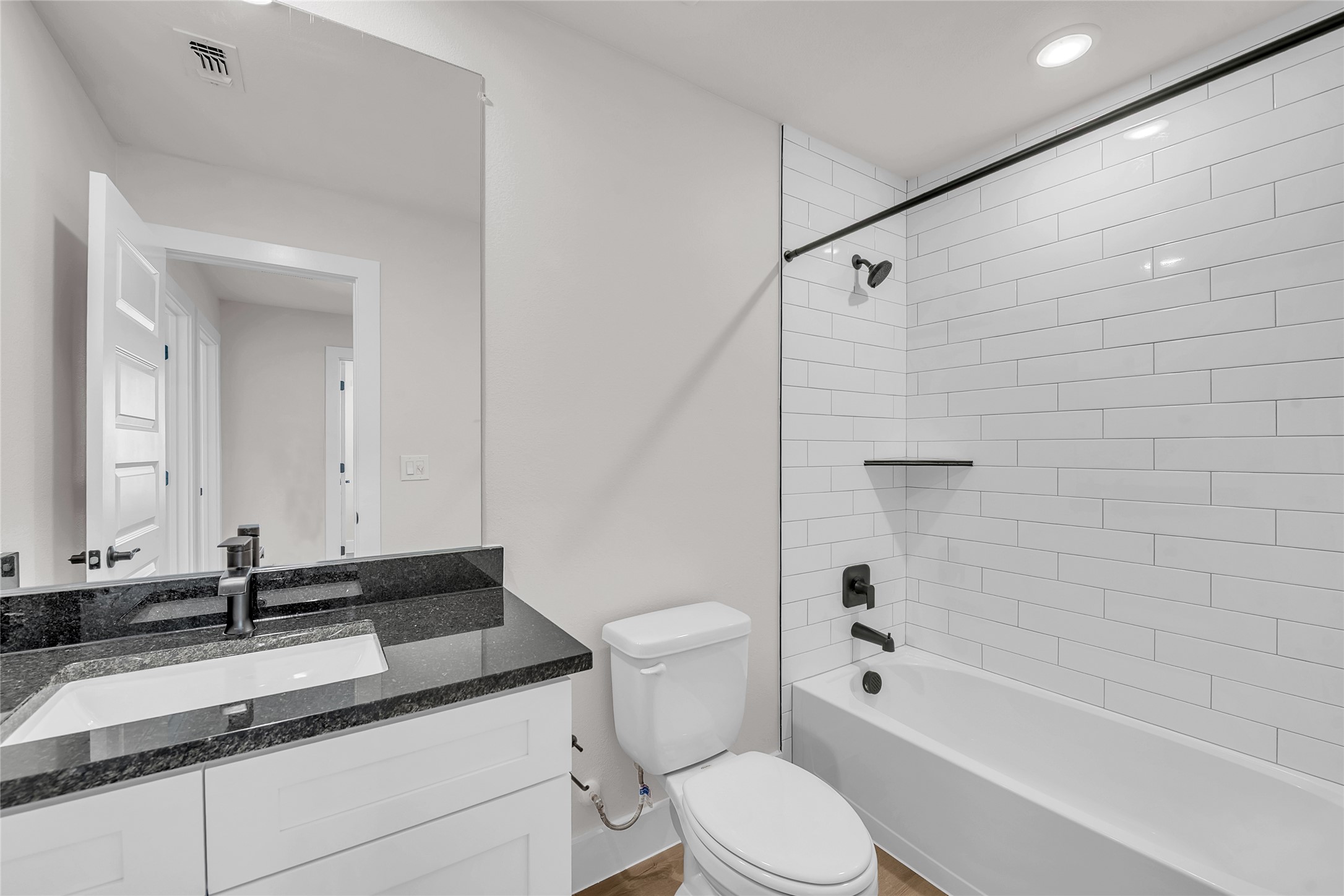 9312 Curious Squirrel Street Austin, TX 78744 - Photo 20 of 22 a bathroom with a granite countertop sink toilet mirror and bathtub