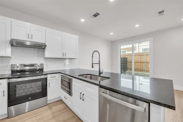 a view of kitchen with kitchen island wooden floor center island and stainless steel appliances