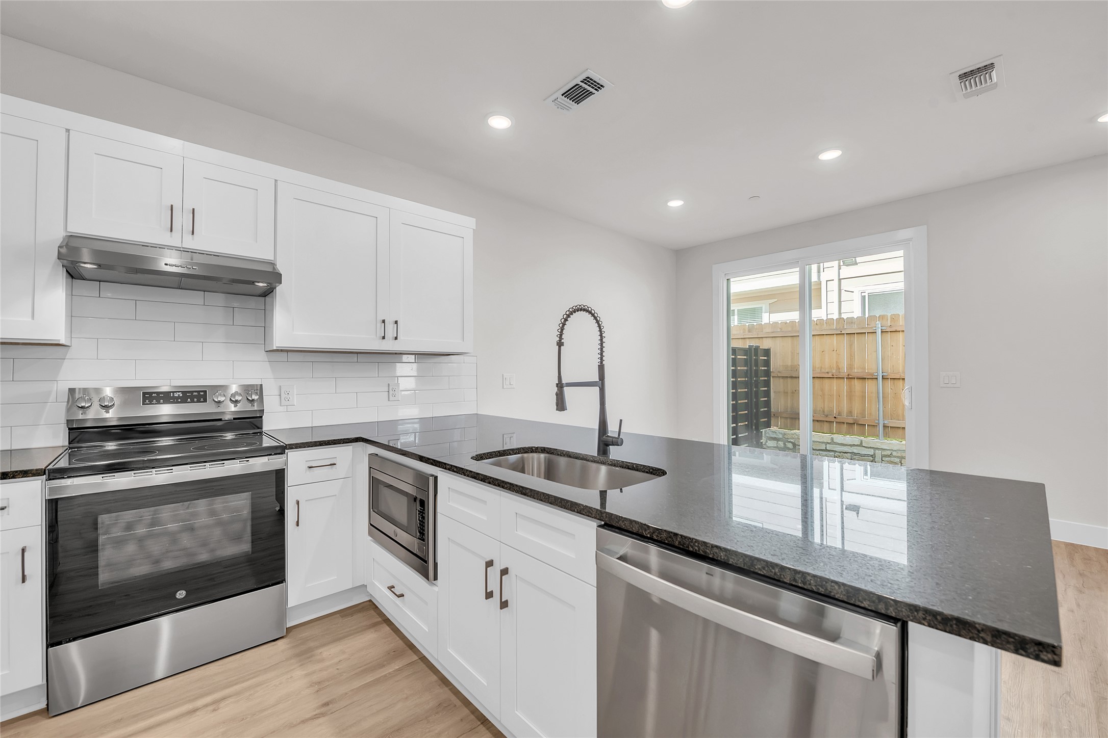 9312 Curious Squirrel Street Austin, TX 78744 - Photo 4 of 22 a kitchen with stainless steel appliances granite countertop a sink a stove and a wooden floors