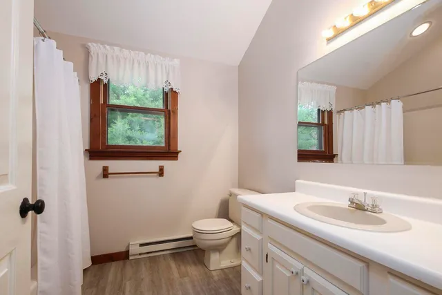 a bathroom with a granite countertop sink toilet a large mirror and a window
