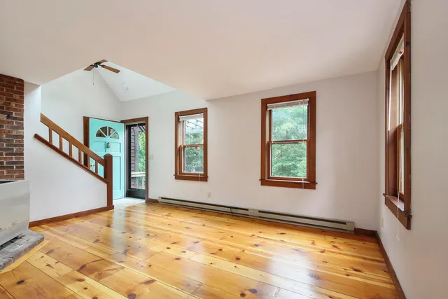 a view of an empty room with window and wooden floor