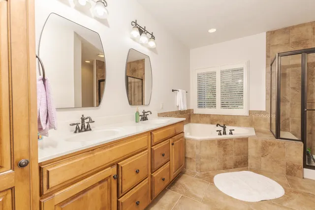 a bathroom with double vanity sinks a large mirror and a bathtub